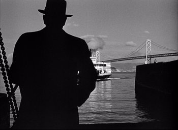 Movie still from “Dark Passage” (1947), directed by Delmer Daves – A black and white photo of a man standing in front of a boat; Wide shot, Low angle