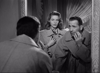 Movie still from “Dark Passage” (1947), directed by Delmer Daves – A man and a woman talking to another man in front of a mirror; Medium shot, Over the shoulder angle