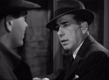 Movie still from “Dark Passage” (1947), directed by Delmer Daves – A black and white photo of a man in a suit and a hat; Close Up shot, Over the shoulder angle