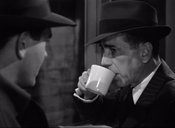 Movie still from “Dark Passage” (1947), directed by Delmer Daves – A man in a hat drinking a cup of coffee; Medium shot, Over the shoulder angle