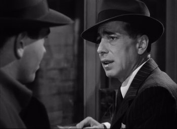 Movie still from “Dark Passage” (1947), directed by Delmer Daves – A black and white photo of a man wearing a hat; Close Up shot, Over the shoulder angle