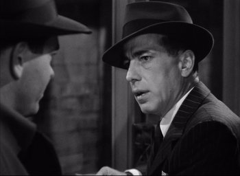 Movie still from “Dark Passage” (1947), directed by Delmer Daves – A black and white photo of a man wearing a hat; Close Up shot, Over the shoulder angle