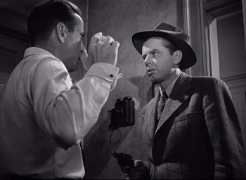 Movie still from “Dark Passage” (1947), directed by Delmer Daves – A man in a hat and a man in a suit holding a camera; Close Up shot, Over the shoulder angle
