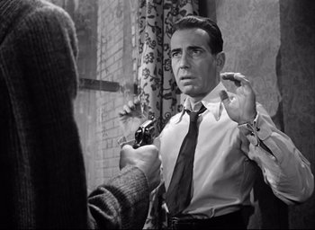 Movie still from “Dark Passage” (1947), directed by Delmer Daves – A black - and - white photo of a man holding a camera; Medium shot, Over the shoulder angle