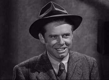 Movie still from “Dark Passage” (1947), directed by Delmer Daves – A man wearing a suit and a hat smiling for the camera; Close Up shot, Over the shoulder angle