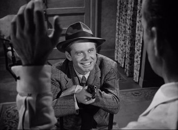 Movie still from “Dark Passage” (1947), directed by Delmer Daves – An old photo of a man in a suit and a hat holding a gun; Close Up shot, Over the shoulder angle