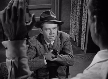 Movie still from “Dark Passage” (1947), directed by Delmer Daves – A black and white photo of a man holding a gun; Medium shot, Over the shoulder angle