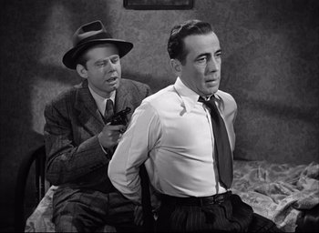 Movie still from “Dark Passage” (1947), directed by Delmer Daves – Two men sitting on a couch one of which is holding a gun; Medium shot, High angle