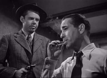 Movie still from “Dark Passage” (1947), directed by Delmer Daves – Two men in suits and ties are smoking a cigarette; Medium shot, Low angle