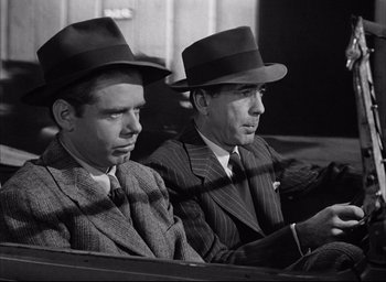 Movie still from “Dark Passage” (1947), directed by Delmer Daves – A couple of men sitting next to each other in suits; Medium shot, Low angle
