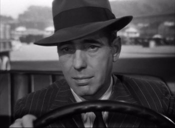 Movie still from “Dark Passage” (1947), directed by Delmer Daves – A black and white photo of a man wearing a hat and driving; Close Up shot, Low angle