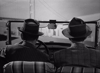 Movie still from “Dark Passage” (1947), directed by Delmer Daves – A couple of men sitting in the back seat of a car; Medium shot, Low angle
