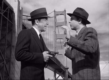 Movie still from “Dark Passage” (1947), directed by Delmer Daves – A couple of men standing next to each other holding guns; Medium shot, Low angle