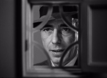 Movie still from “Dark Passage” (1947), directed by Delmer Daves – A black and white photo of a man looking through a window; Close Up shot, Low angle