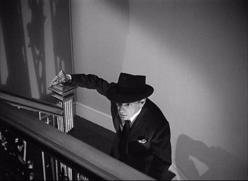Movie still from “Dark Passage” (1947), directed by Delmer Daves – A black and white photo of a man leaning on a railing; Medium shot, High angle