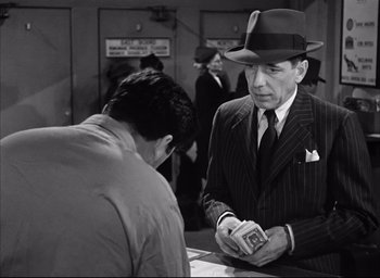 Movie still from “Dark Passage” (1947), directed by Delmer Daves – An older man wearing a hat and a suit and tie; Medium shot, Over the shoulder angle