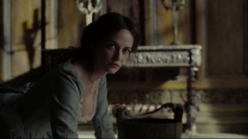 Movie still from “Dark Shadows” (2012), directed by Tim Burton – A beautiful woman sitting on a chair in front of a fireplace; Medium shot, Over the shoulder angle