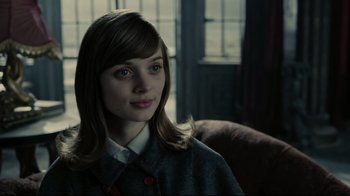 Movie still from “Dark Shadows” (2012), directed by Tim Burton – A young woman sitting on a chair in a room; Close Up shot, Over the shoulder angle