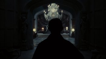 Movie still from “Dark Shadows” (2012), directed by Tim Burton – A man standing in front of a chandelier in a dark room; Wide shot, Low angle