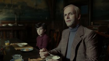 Movie still from “Dark Shadows” (2012), directed by Tim Burton – A man sitting at a dinner table with a child; Medium shot, Low angle