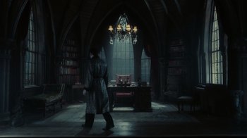 Movie still from “Dark Shadows” (2012), directed by Tim Burton – A person walking in a room with a desk and chair in the background; Wide shot, High angle