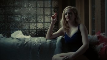 Movie still from “Dark Shadows” (2012), directed by Tim Burton – A woman sitting on top of a couch smoking a cigarette; Medium shot, Low angle