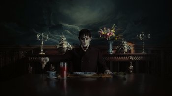 Movie still from “Dark Shadows” (2012), directed by Tim Burton – A man sitting at a table with a plate in front of him; Medium shot, High angle