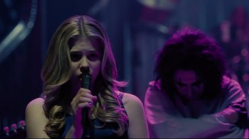 Movie still from “Dark Shadows” (2012), directed by Tim Burton – A woman holding a microphone while another woman looks on; Medium shot, Over the shoulder angle