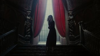 Movie still from “Dark Shadows” (2012), directed by Tim Burton – A woman standing on some steps in front of a window; Wide shot, Low angle