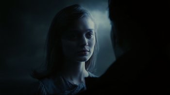 Movie still from “Dark Shadows” (2012), directed by Tim Burton – A young woman looking into a mirror in a dimly - lit room; Close Up shot, Over the shoulder angle