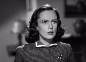 Movie still from “Dark Victory” (1939), directed by Edmund Goulding – A woman in a jacket and a brooch is looking to her left; Close Up shot, Over the shoulder angle