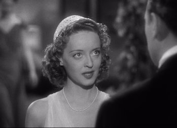 Movie still from “Dark Victory” (1939), directed by Edmund Goulding – A young woman wearing a white dress and a pearl necklace; Close Up shot, Over the shoulder angle