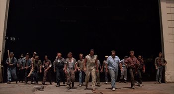 Movie still from “Darkman” (1990), directed by Sam Raimi – A group of men are standing on a stage; Wide shot, Low angle