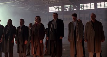 Movie still from “Darkman” (1990), directed by Sam Raimi – A group of men in suits and ties standing in an industrial setting; Wide shot, Low angle