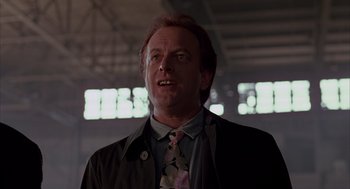 Movie still from “Darkman” (1990), directed by Sam Raimi – A man in a black jacket and a pink tie; Close Up shot, Low angle