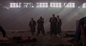 Movie still from “Darkman” (1990), directed by Sam Raimi – A group of men standing next to each other in an abandoned building; Wide shot, Low angle
