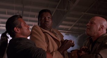 Movie still from “Darkman” (1990), directed by Sam Raimi – A man in a brown robe is holding a cigarette; Close Up shot, Low angle