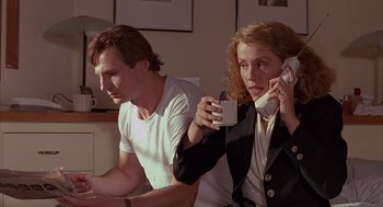 Movie still from “Darkman” (1990), directed by Sam Raimi – A man and a woman sitting next to each other holding coffee cups; Medium shot, Low angle