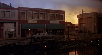 Movie still from “Darkman” (1990), directed by Sam Raimi – The sun is setting over a city street; Extreme Wide shot, Low angle