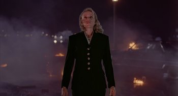 Movie still from “Darkman” (1990), directed by Sam Raimi – A woman in a black suit standing in front of a street light; Medium shot, Low angle