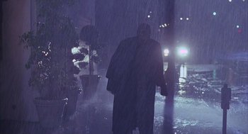 Movie still from “Darkman” (1990), directed by Sam Raimi – A man walking down a street in the rain; Wide shot, Low angle