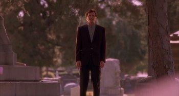 Movie still from “Darkman” (1990), directed by Sam Raimi – A man in a suit standing in front of a tree; Wide shot, Low angle