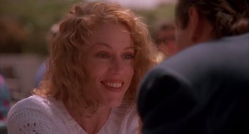 Movie still from “Darkman” (1990), directed by Sam Raimi – A person with curly red hair smiling; Close Up shot, Over the shoulder angle
