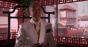 Movie still from “Darkman” (1990), directed by Sam Raimi – An older man wearing a white suit and tie; Medium shot, Low angle