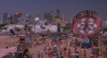 Movie still from “Darkman” (1990), directed by Sam Raimi – A crowd of people standing around a carnival; Extreme Wide shot, High angle