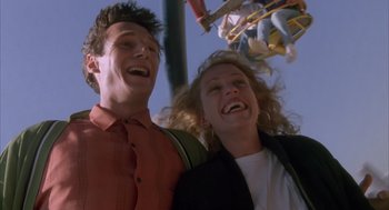 Movie still from “Darkman” (1990), directed by Sam Raimi – A man and a woman are laughing together; Medium shot, Low angle