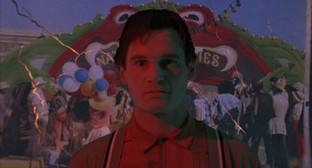 Movie still from “Darkman” (1990), directed by Sam Raimi – A man in a red shirt is standing in front of a carnival float; Close Up shot, Low angle