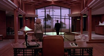 Movie still from “Darkman” (1990), directed by Sam Raimi – A man and a woman standing in front of a large window; Extreme Wide shot, Low angle