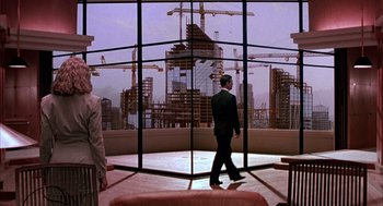 Movie still from “Darkman” (1990), directed by Sam Raimi – A man in a suit walking in front of a large window; Wide shot, Low angle