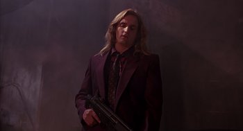 Movie still from “Darkman” (1990), directed by Sam Raimi – A man in a suit and tie holding a gun; Medium shot, Low angle